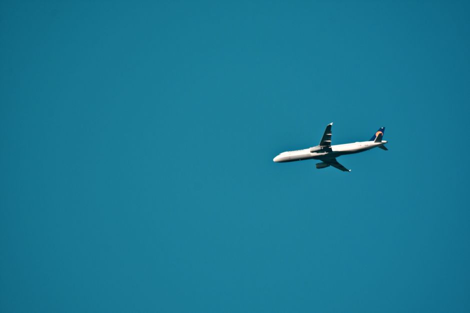 A commercial airplane flying against a clear blue sky, capturing the essence of travel and