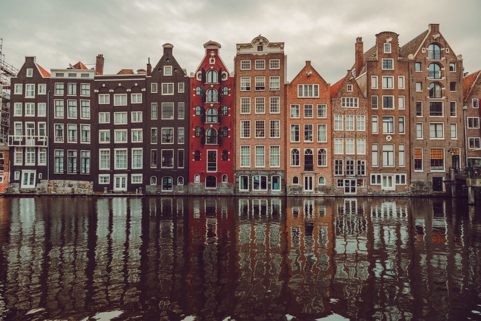 Scenic view of colorful canal houses in Amsterdam with water reflections, capturing urban architecture.