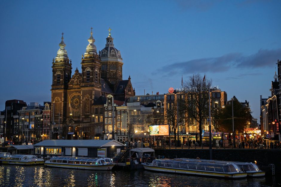 Charming evening view of the Basilica of St. Nicholas by the canal in Amsterdam.