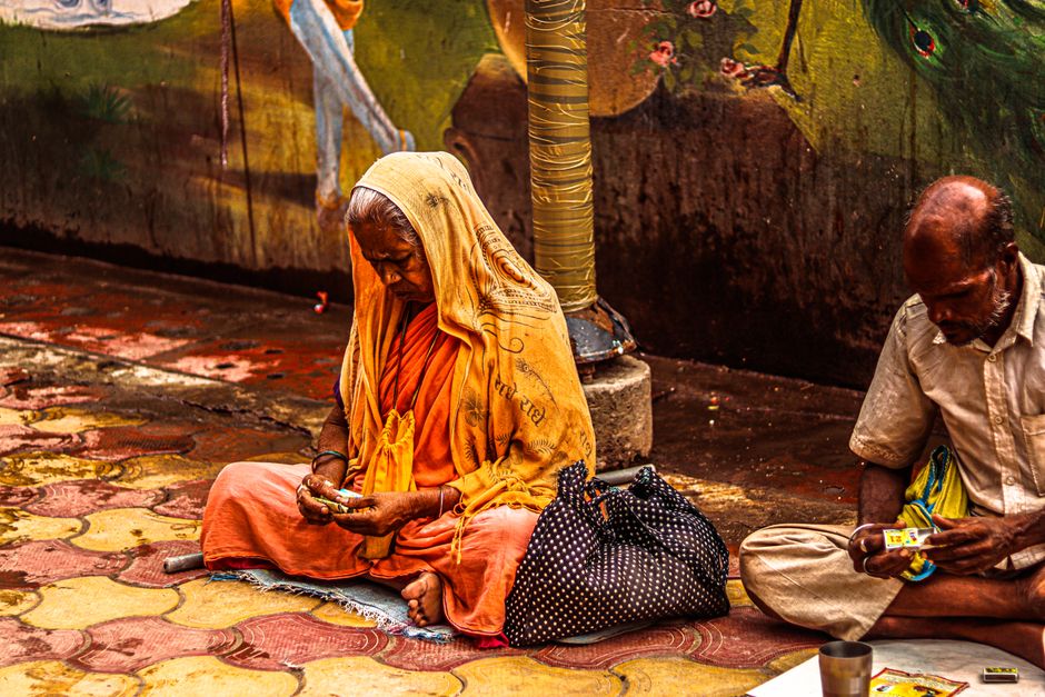 Elderly couple sits on a colorful street, immersed in daily activities.