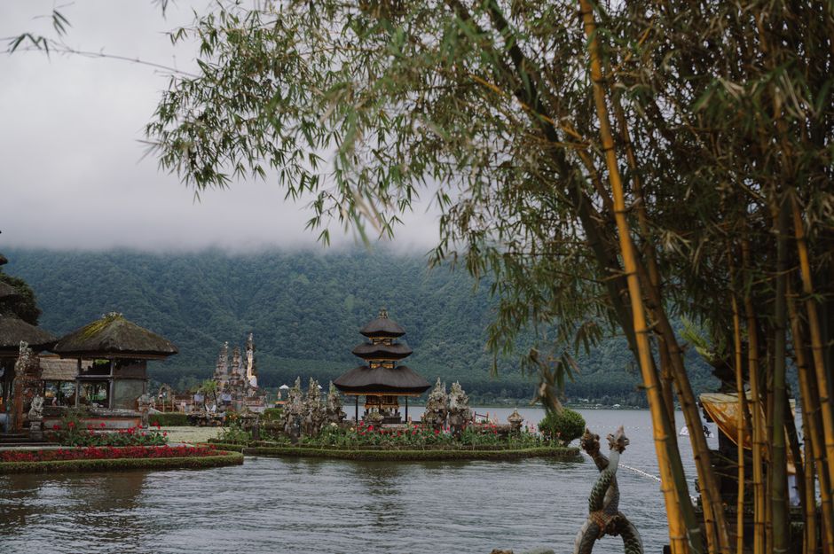 A tranquil scene of the Ulun Danu Beratan Temple in Bali, surrounded by lush greenery and misty mountains.