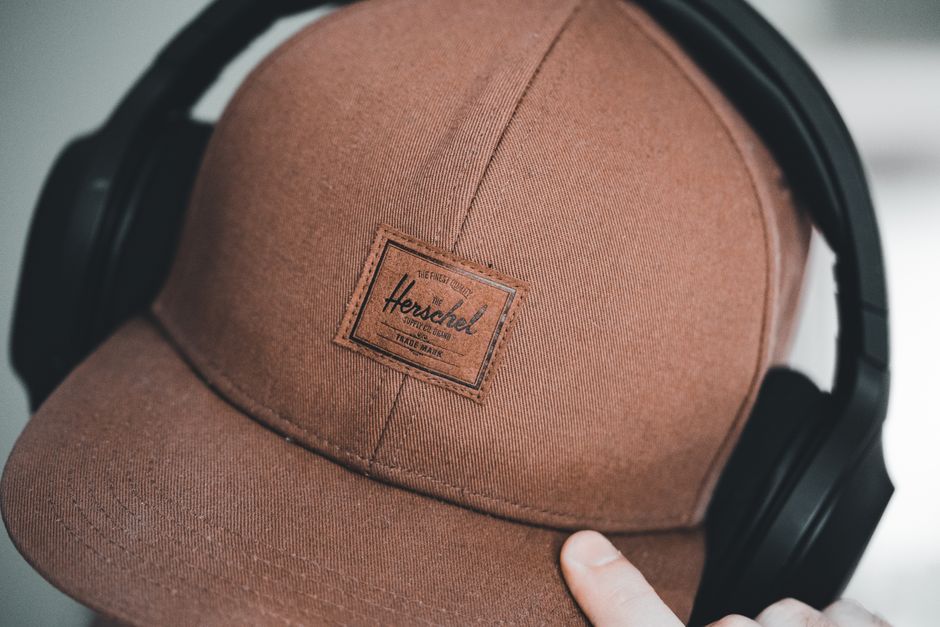 Brown cap with logo worn with black headphones, showcasing stylish accessory and fashion.