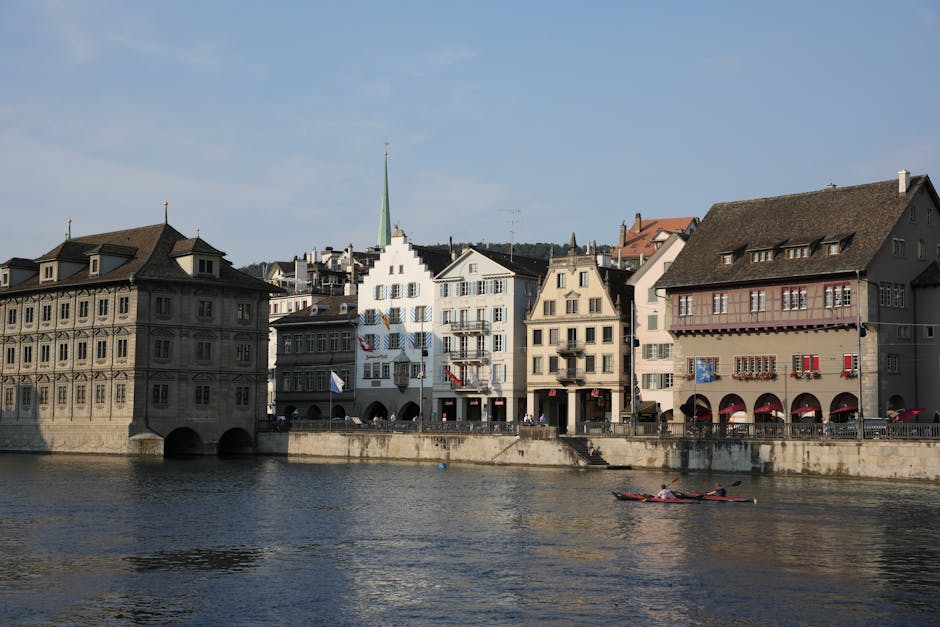 Scenic view of Zürich's historic buildings and canoeing on the Limmat River.