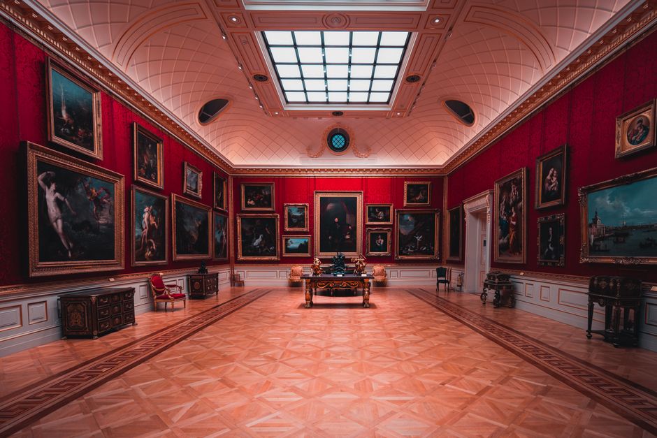 Explore the grandeur of an art gallery room in London with elegant red walls and classic p