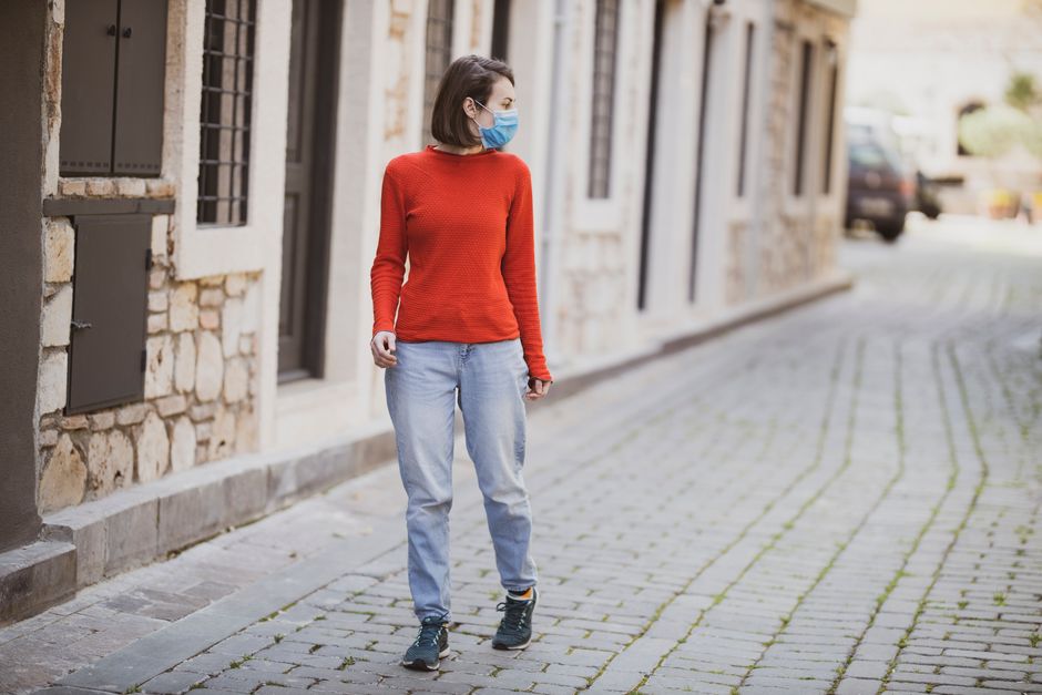 A woman wearing a mask walks through a cobblestone street in Antalya, Turkey.