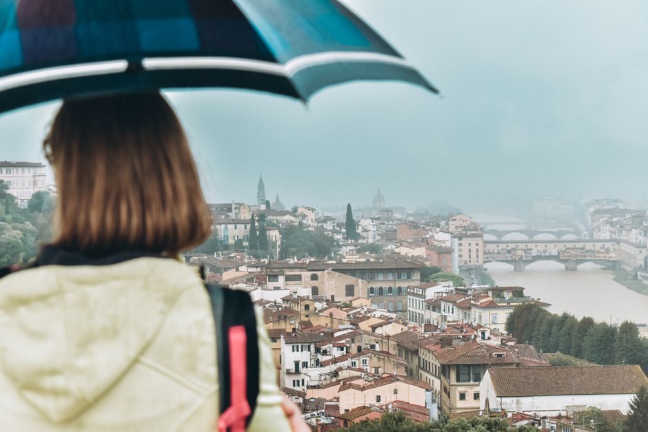 A person under an umbrella overlooking Florence, Italy with a view of Ponte Vecchio.