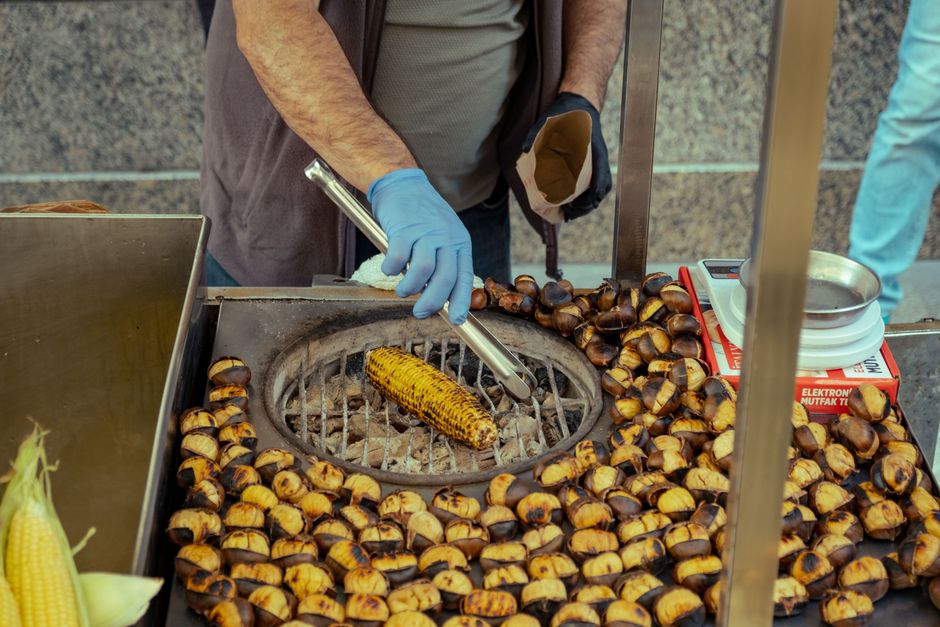 Street vendor preparing roasted corn and chestnuts at an urban food stand.