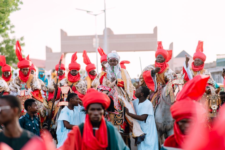 Vibrant celebration showcasing men in red attire on horses during cultural festival parade.