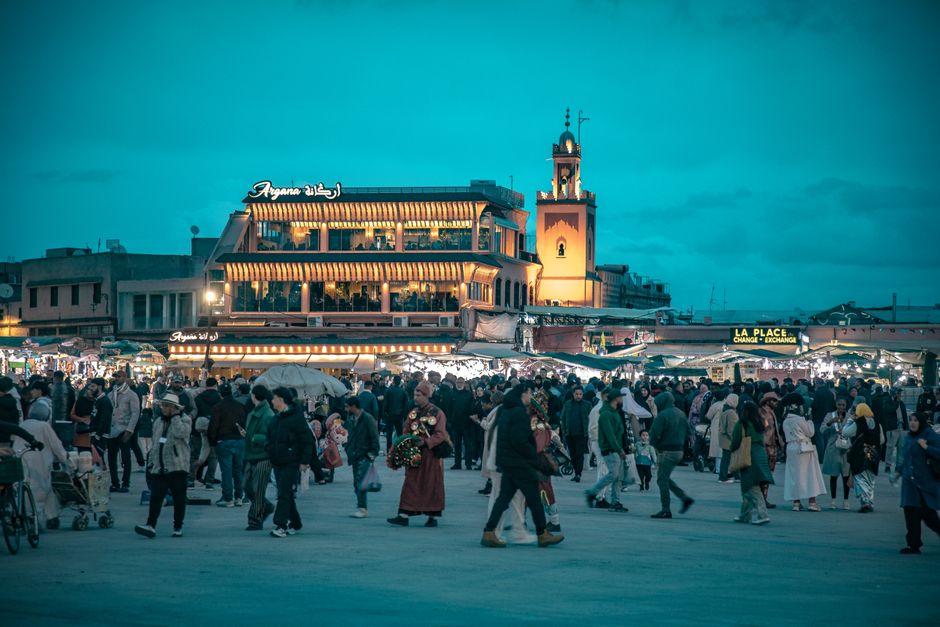 Crowd gathered at iconic Jemaa el-Fnaa square in Marrakesh during dusk, vibrant and lively atmosphere.