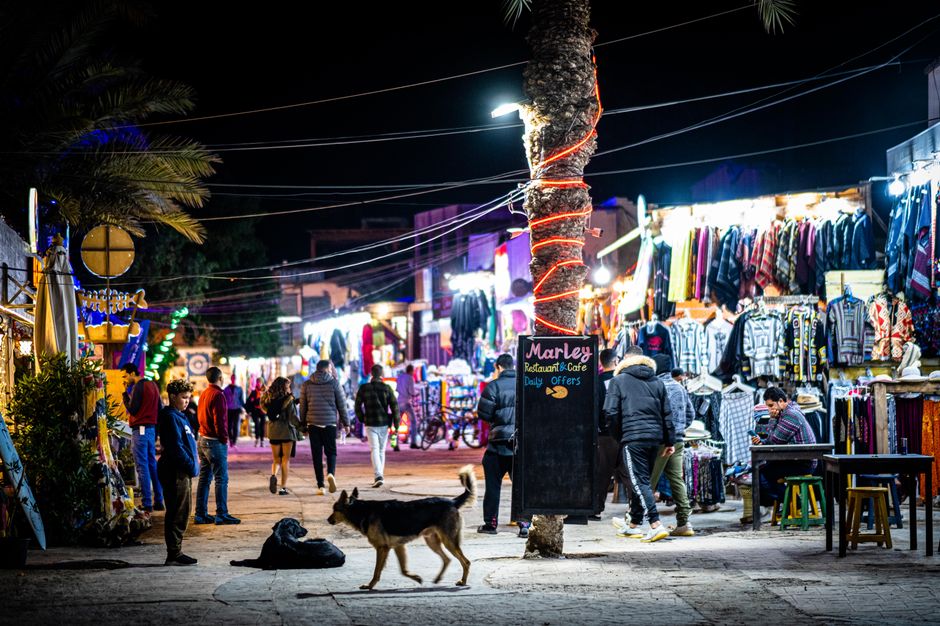 Vibrant outdoor night market with illuminated stalls, shoppers, and vendors.