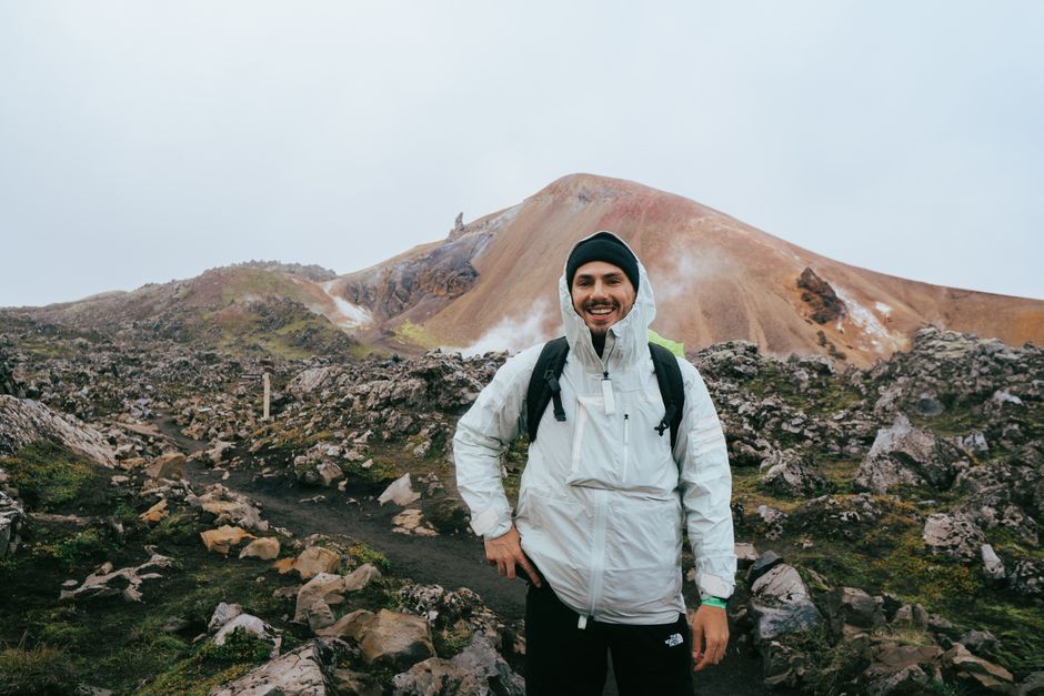 Smiling traveler in Icelandic highlands against colorful volcanic mountains.