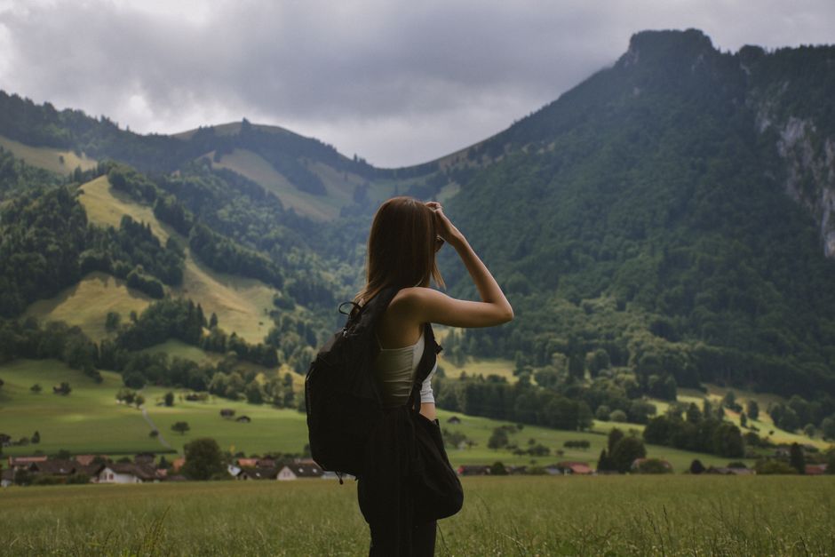 Young woman with backpack admiring stunning mountain landscape on a cloudy day.