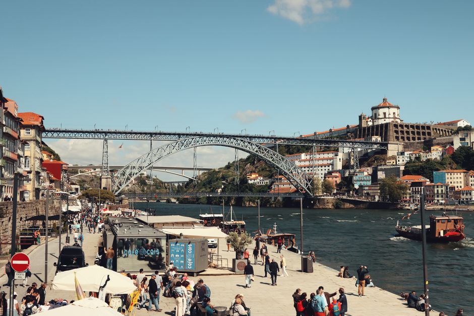 Bustling scene of the Dom Luís I Bridge over the Douro River in Porto with tourists and cityscape.