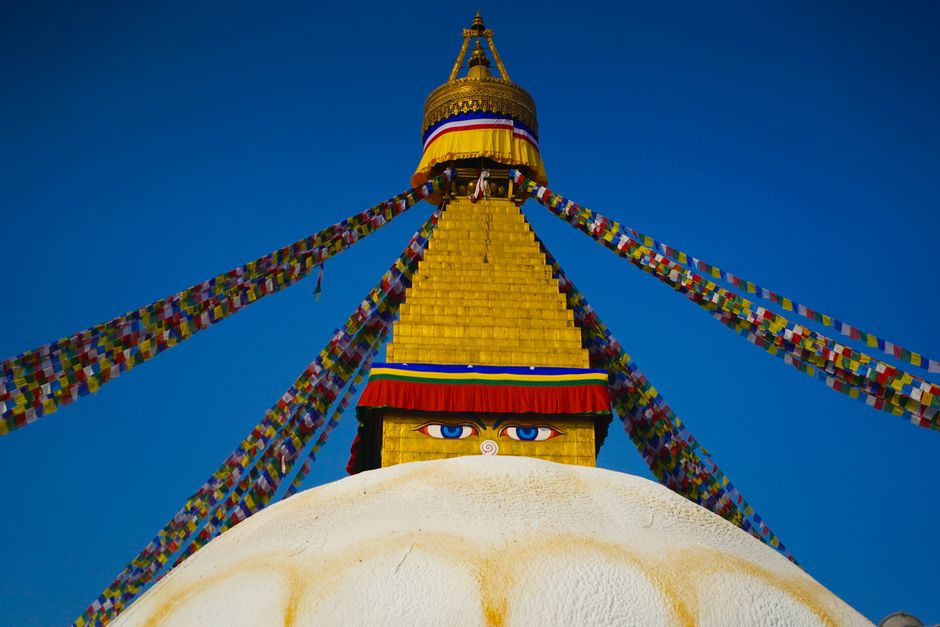 The majestic Boudhanath Stupa in Kathmandu, adorned with prayer flags under a blue sky.