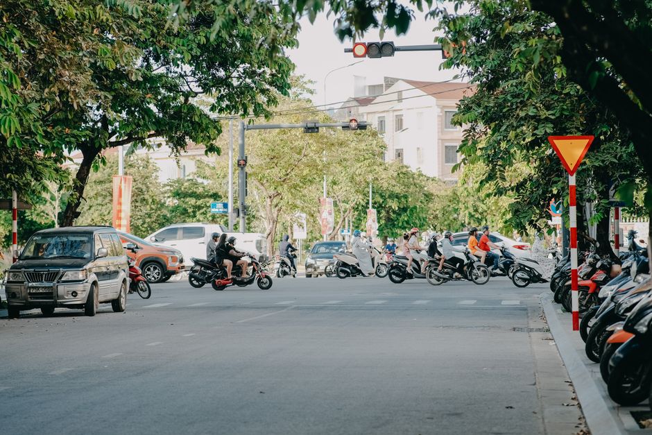 A bustling city street scene with motorcycles and cars at an intersection during the day.