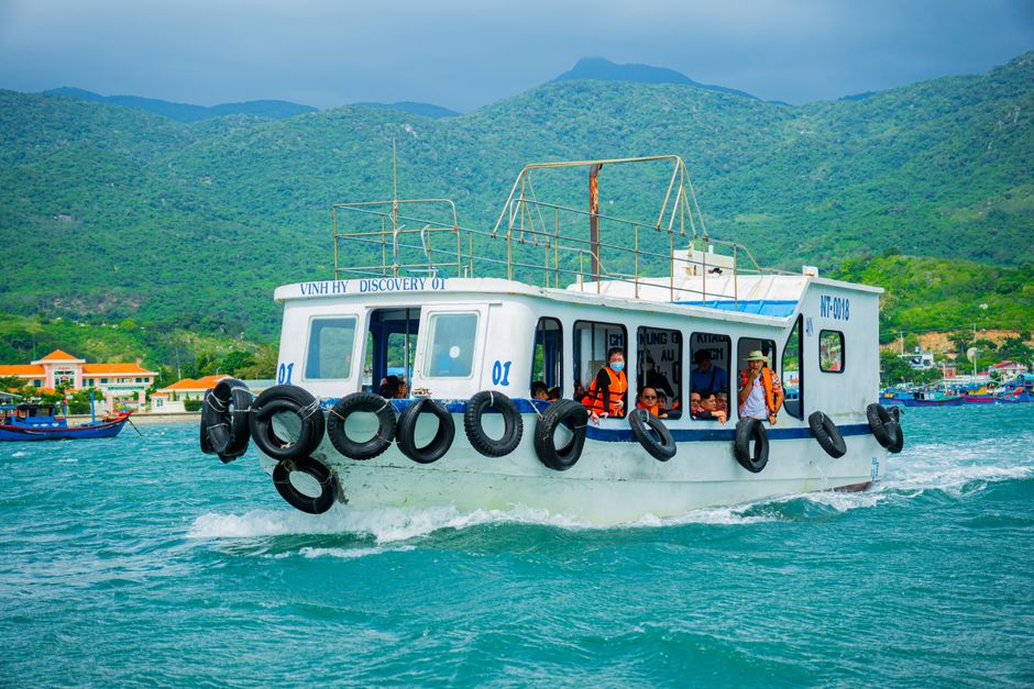 Tourists enjoy a boat ride in picturesque Vinh Hy Bay surrounded by lush mountains.