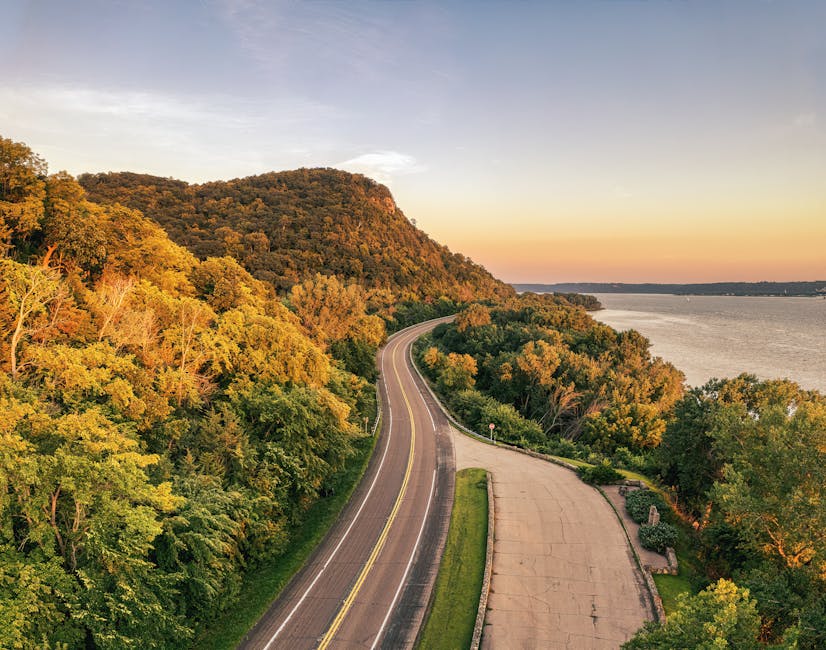 Aerial view of winding highway beside lush foliage and river in Stockholm, Wisconsin at sunset.