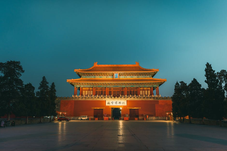 Beautifully illuminated Gate of Divine Prowess fronting Beijing's historic Forbidden City at dusk.