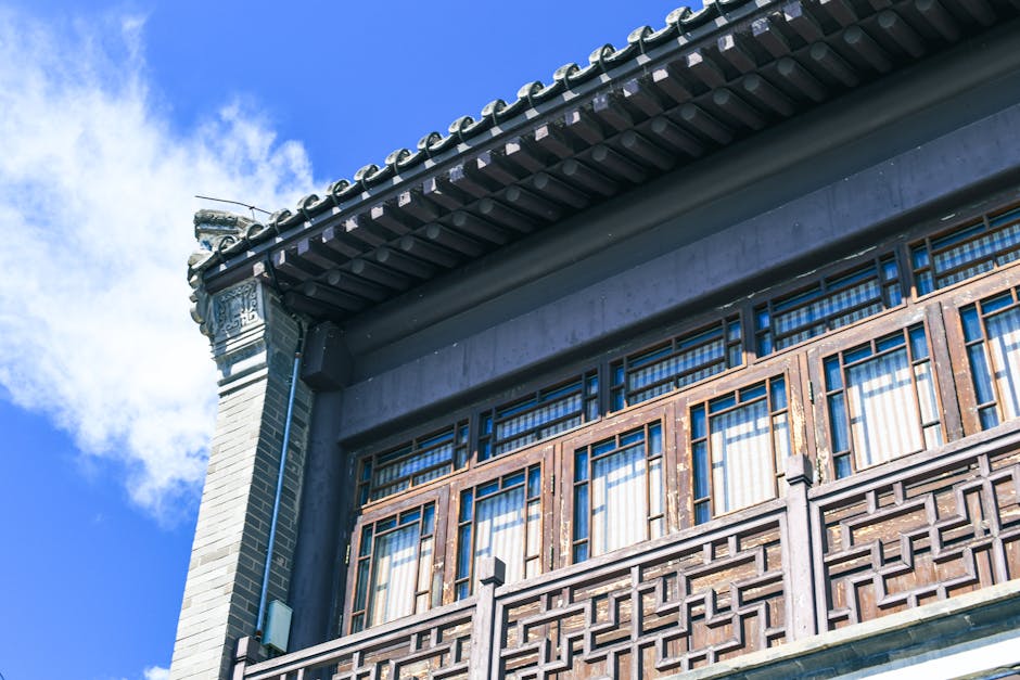 Low-angle view of traditional Asian building with wooden details against a clear blue sky.
